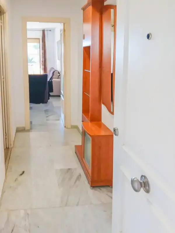 Un pasillo con almacenamiento de madera empotrado conduce a una sala de estar.