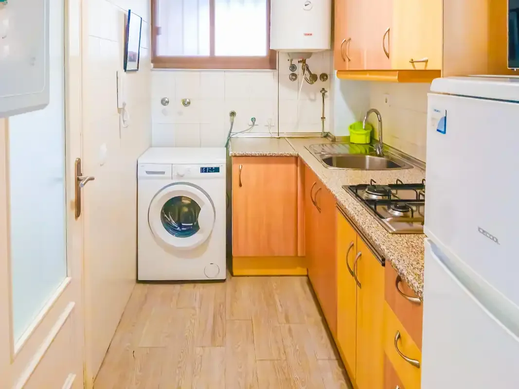 Una cocina compacta con armarios de madera, un fregadero y electrodomésticos.