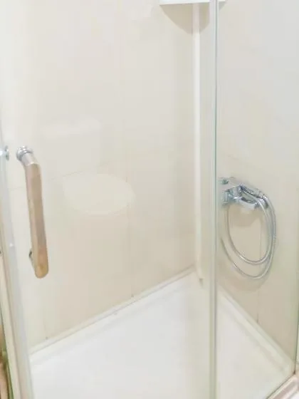 Una ducha con paneles de vidrio y un cabezal de ducha de mano montado en la pared.