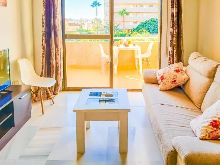 Una sala de estar con asientos, una mesa de centro y puertas corredizas de vidrio que dan a un balcón.