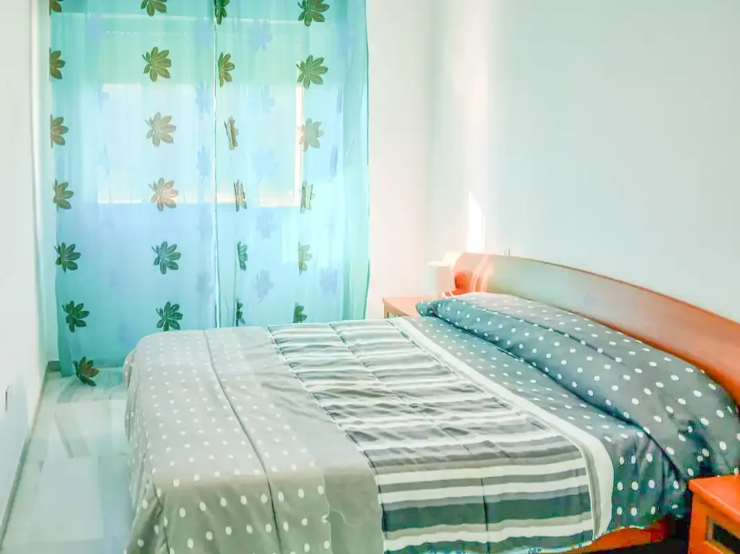 Un dormitorio con una cama cubierta de ropa de cama estampada junto a una ventana.