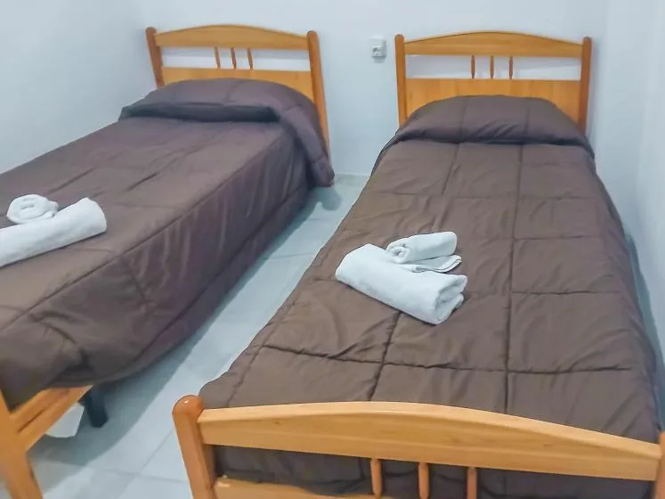 Dormitorio con dos camas individuales, cada una con toallas blancas dobladas.