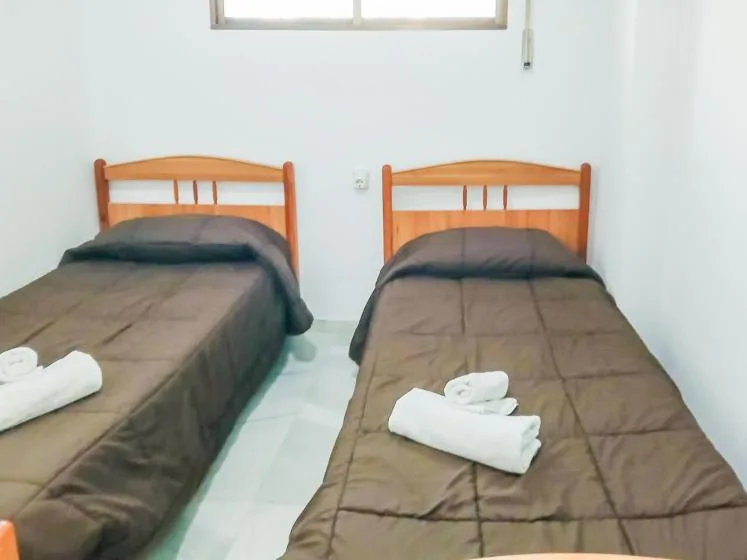 Un dormitorio con dos camas individuales y toallas dobladas sobre la ropa de cama.