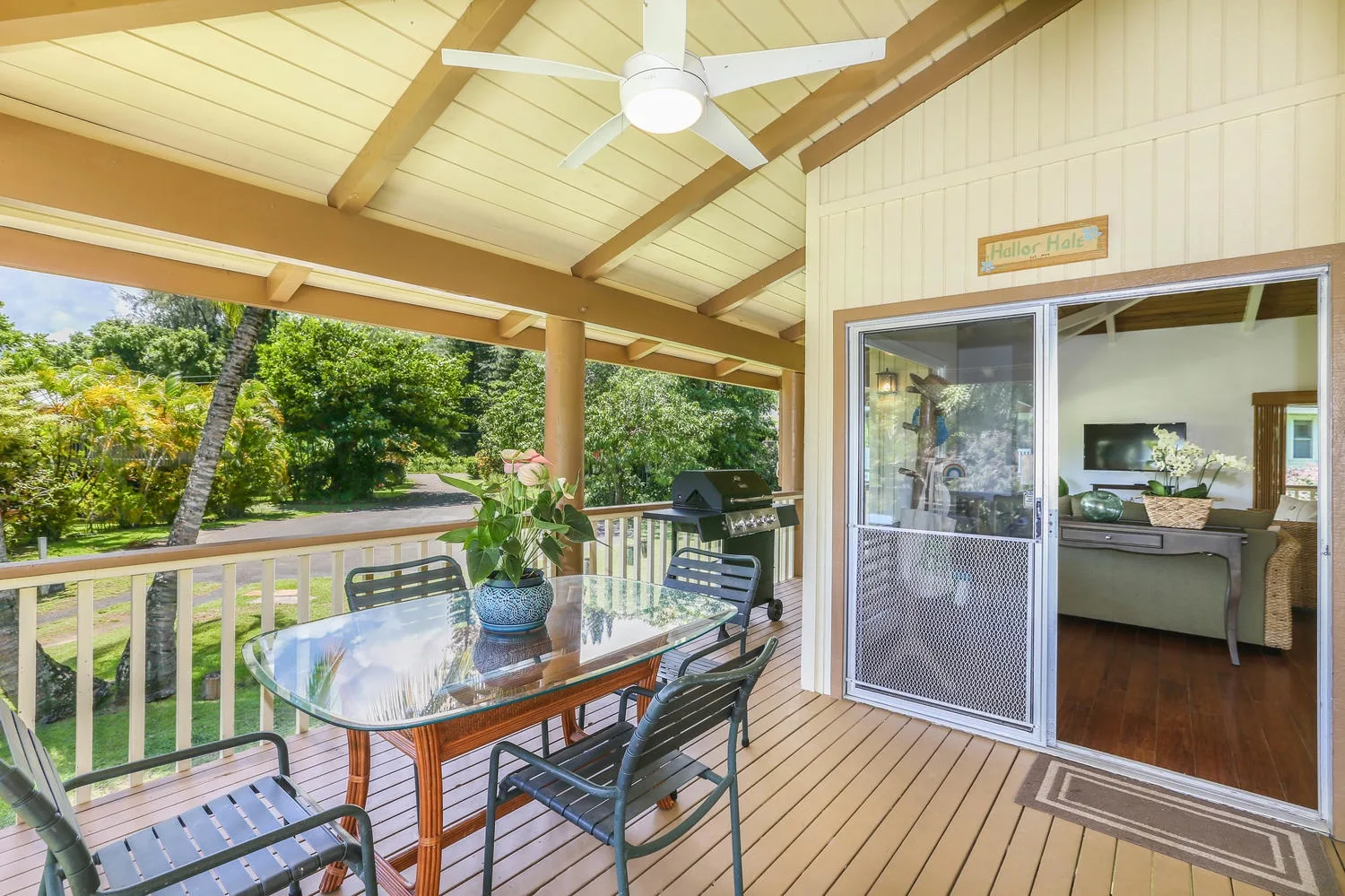 A covered outdoor seating area with a glass-top table beside an open sliding door.