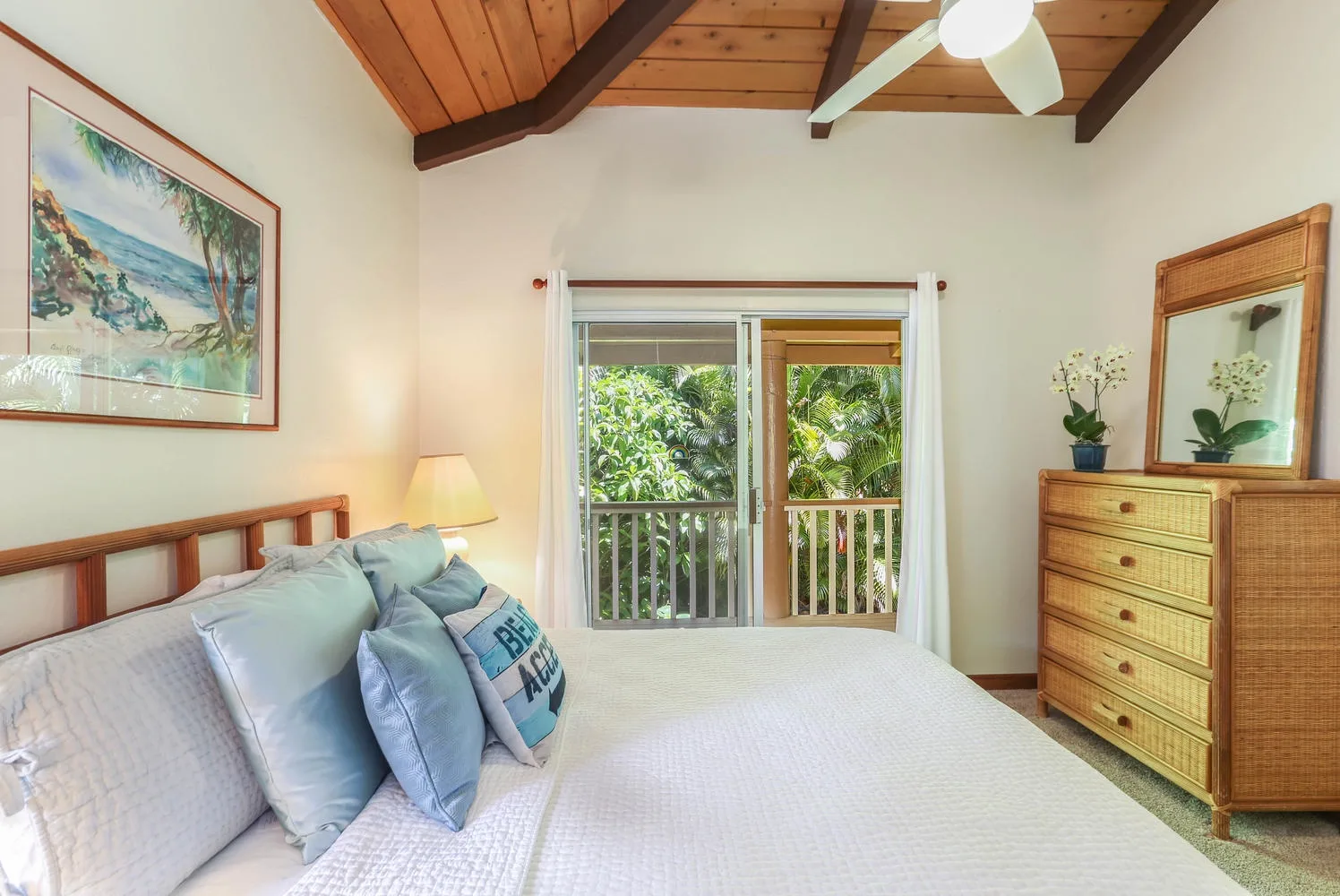 A bedroom with a bed beside a window overlooking greenery.