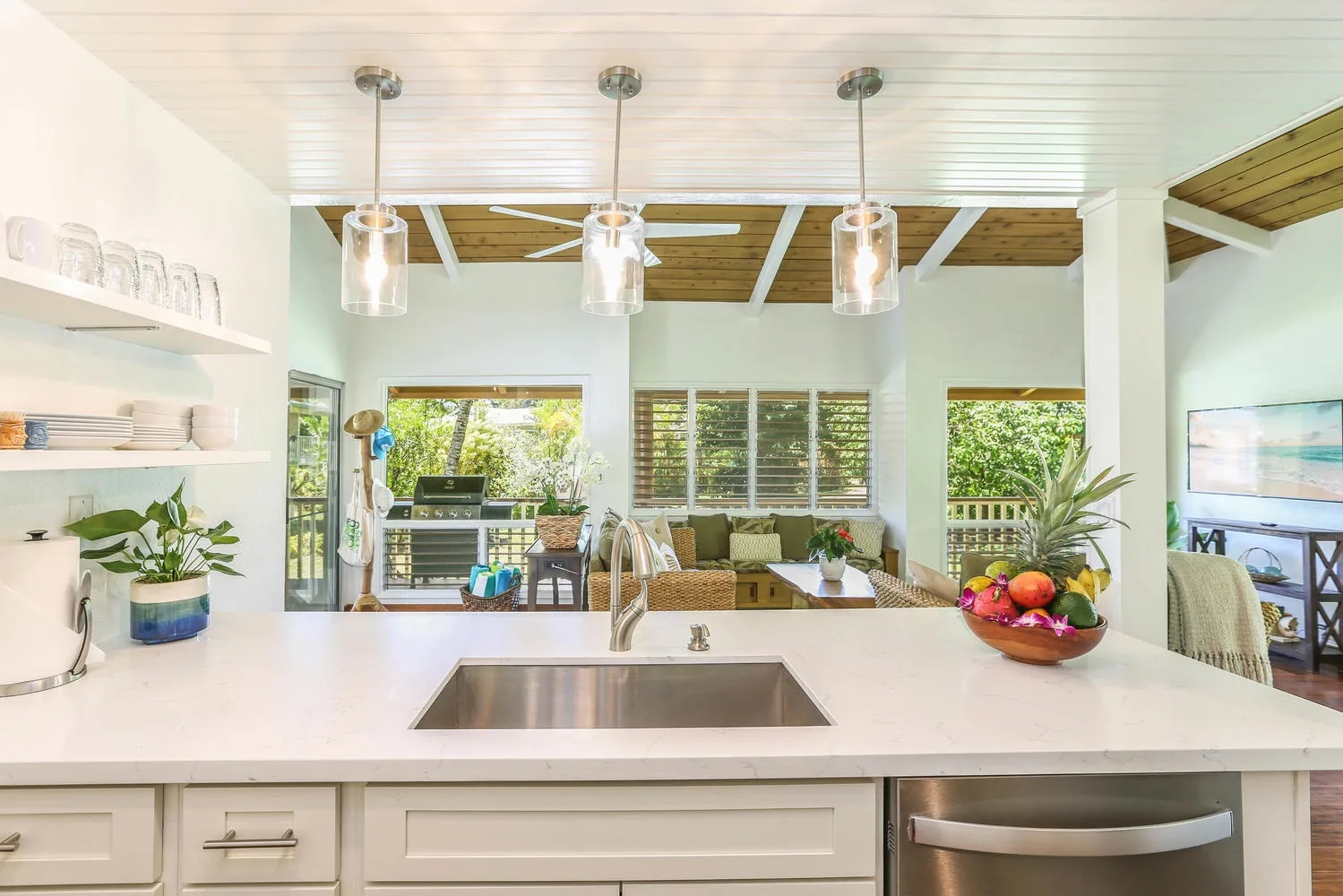 A bright open kitchen overlooks a living area, with a wide counter and sink.