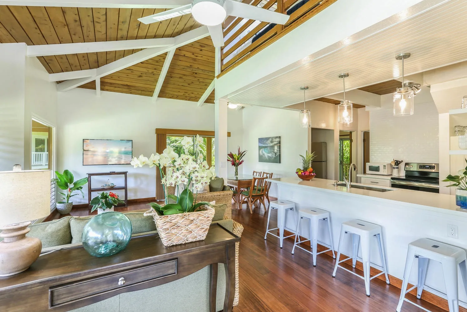 An open-plan living and kitchen area with a long counter and high stools.