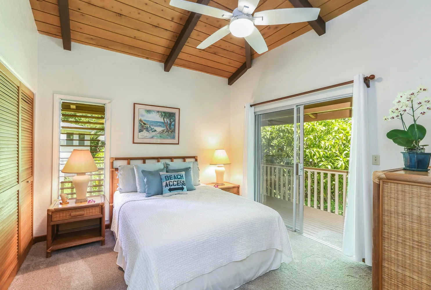 A bedroom with a neatly made bed beside sliding glass doors opening to a balcony.