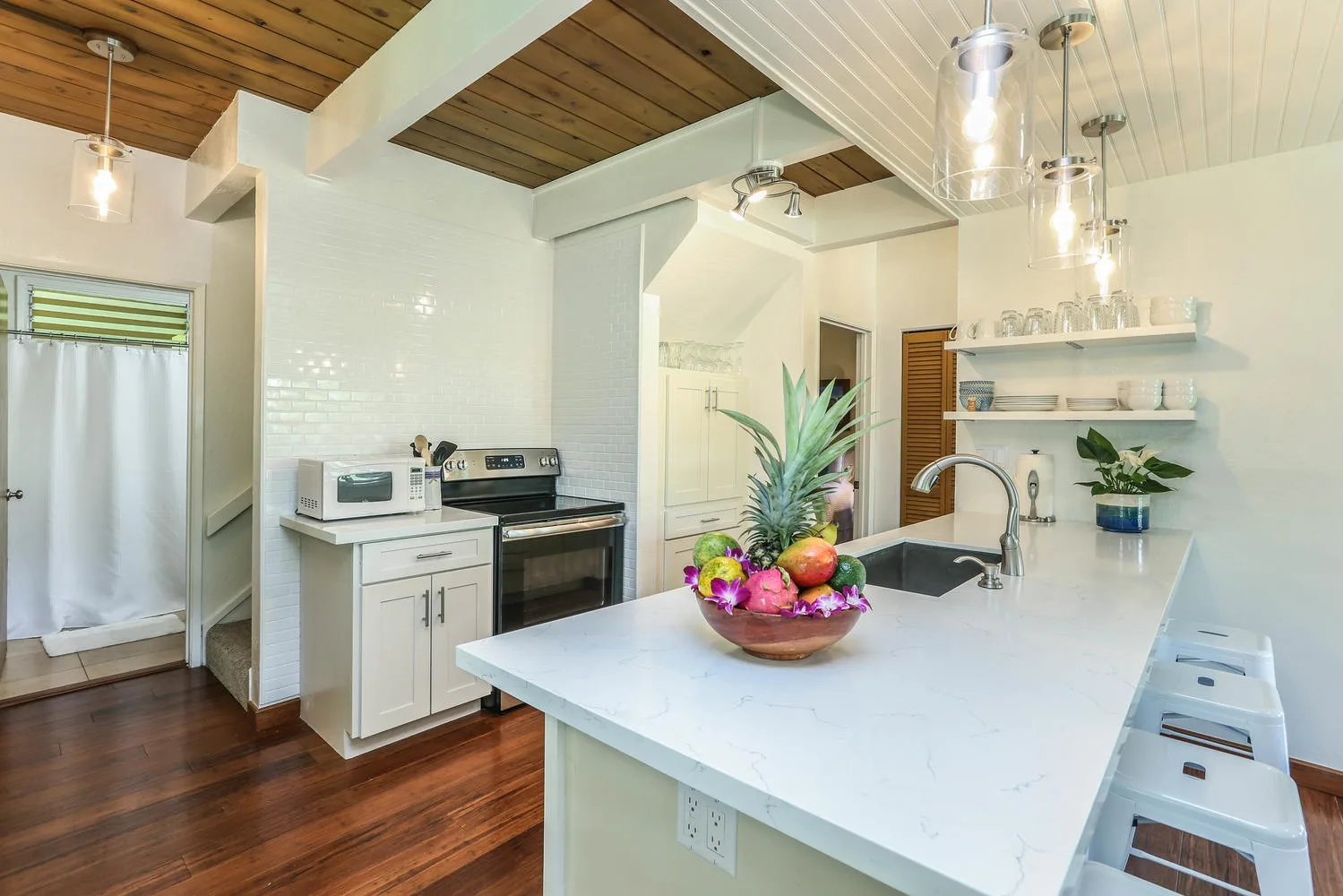 A bright kitchen with a large island, sink, and fruit bowl.