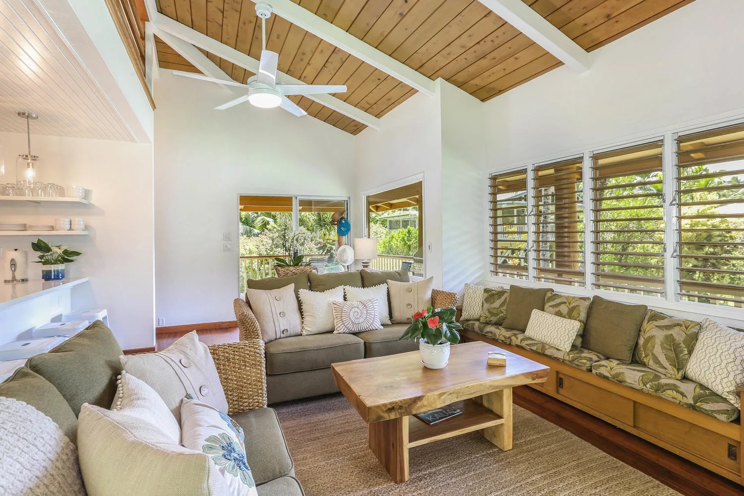A bright living room with cushioned seating, a wooden coffee table, and large windows.