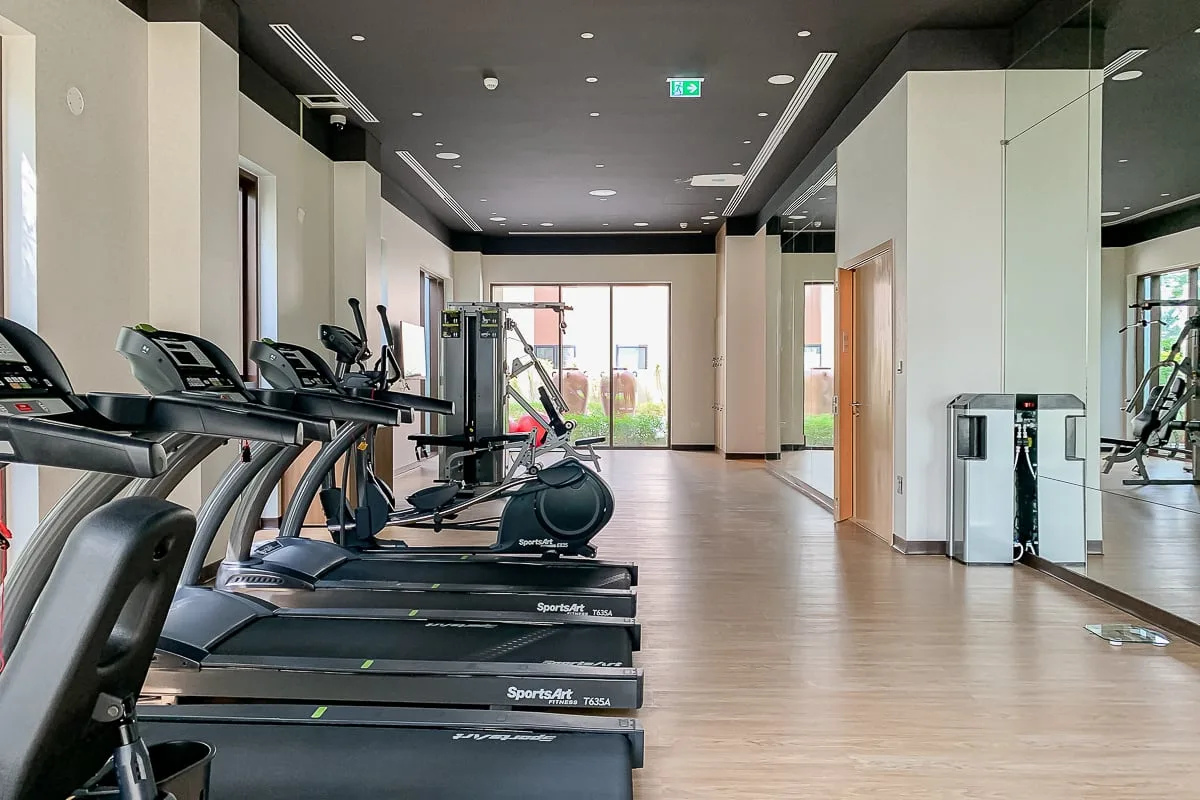 A fitness room with exercise machines arranged along one side.