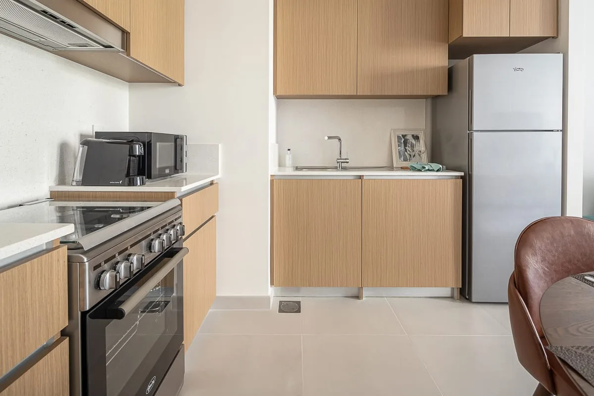 A modern kitchen with wood cabinetry, stainless steel appliances, and a dining table.