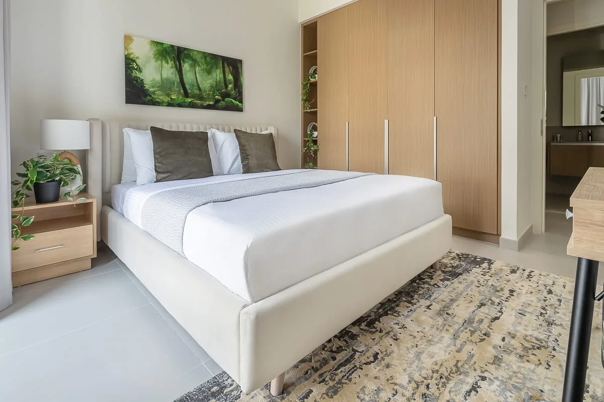 A bedroom with a neatly made bed and a large wooden wardrobe.