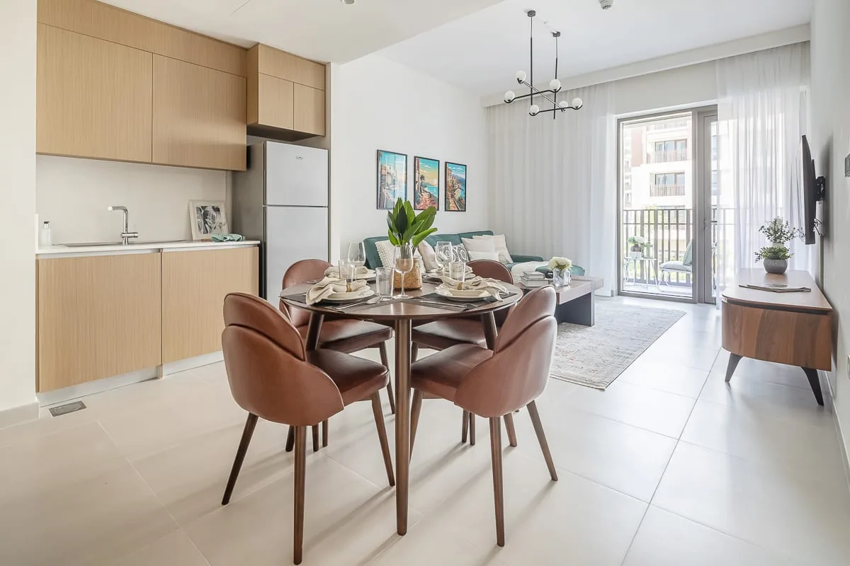 A bright open-plan dining and living area with a table set beside the kitchen.