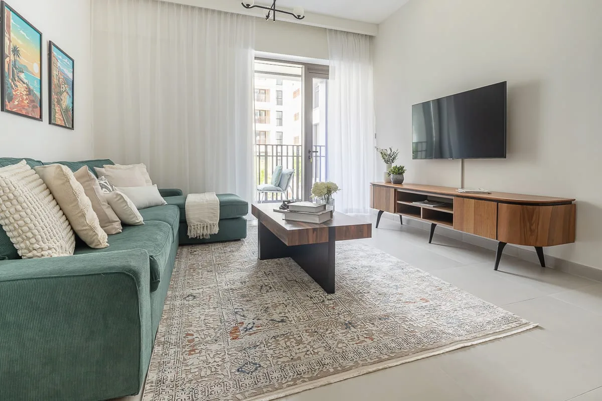 A bright living room with teal seating, a coffee table, and a television.