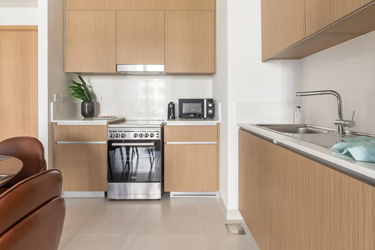 A modern kitchen with wood cabinetry, a stove, and a sink.