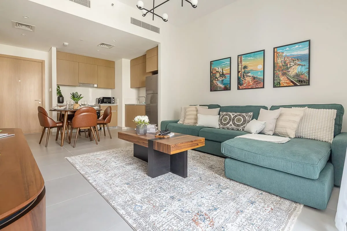 Una sala y comedor de planta abierta con asientos verde azulado y una mesa de comedor de madera.