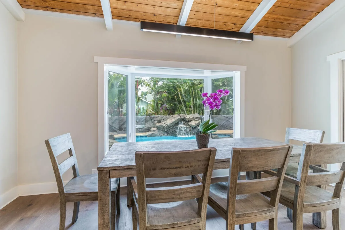 A dining area with a wooden table and chairs beside a large window.