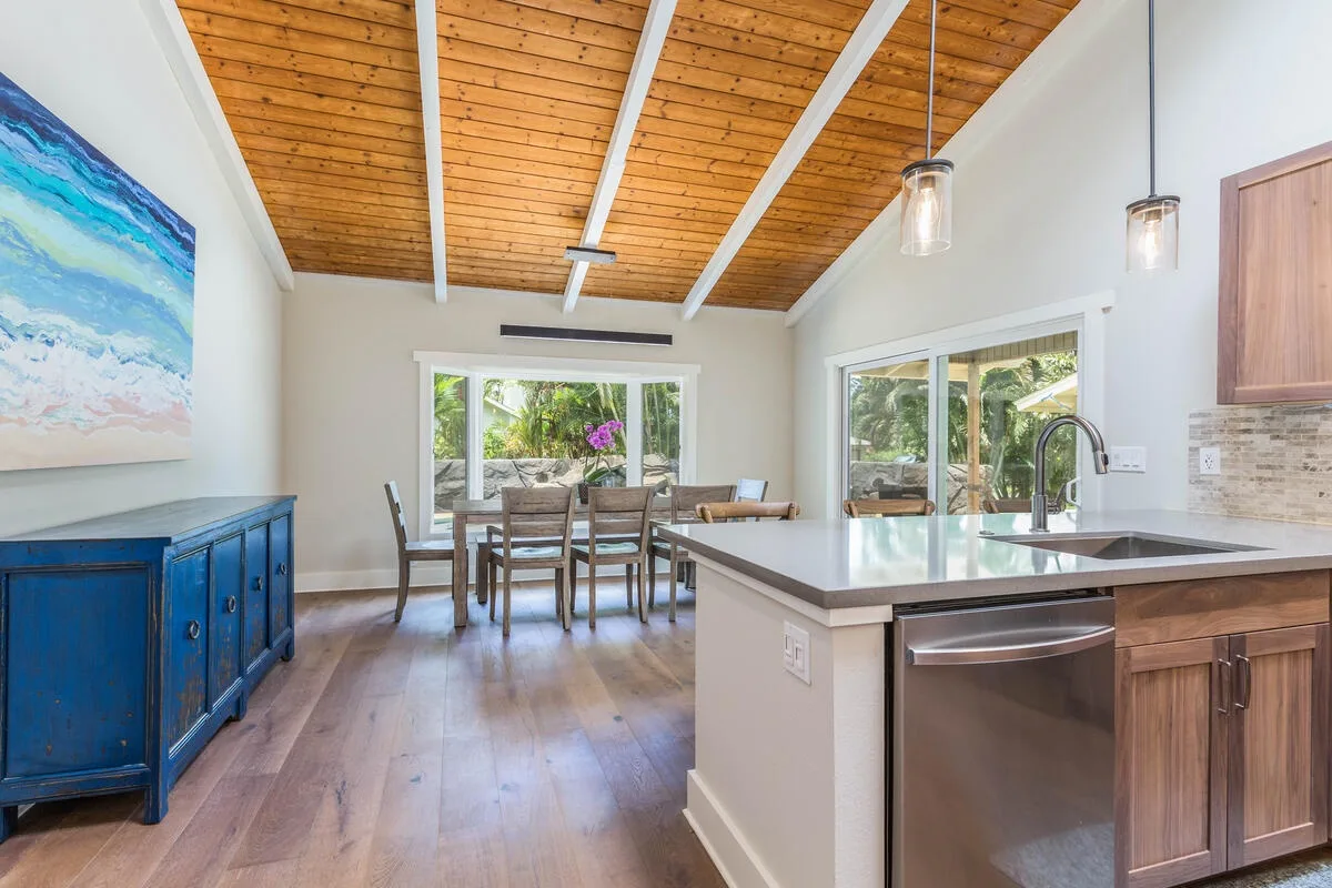 A bright kitchen and dining area with a wood ceiling and large windows.