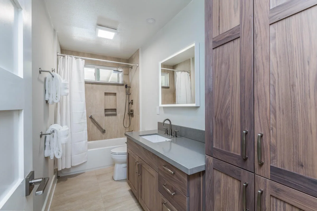 A bathroom with a vanity, mirror, and shower.