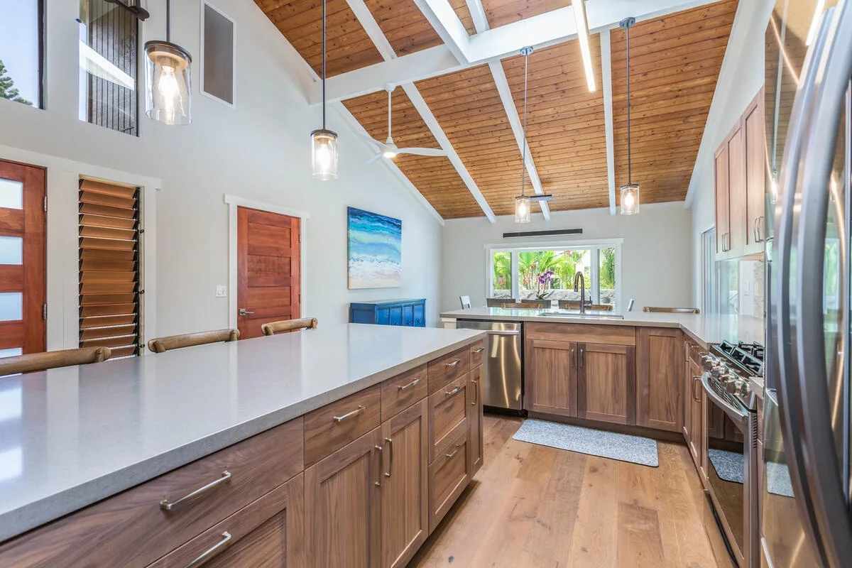 A bright kitchen with wooden cabinets, a central island, and a large window.
