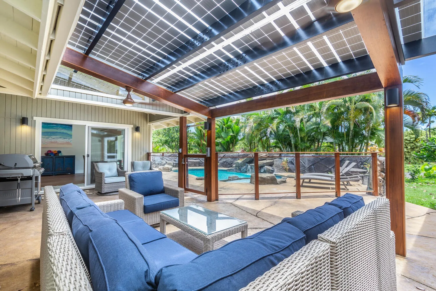 Un salón exterior cubierto con asientos acolchados da a una piscina.