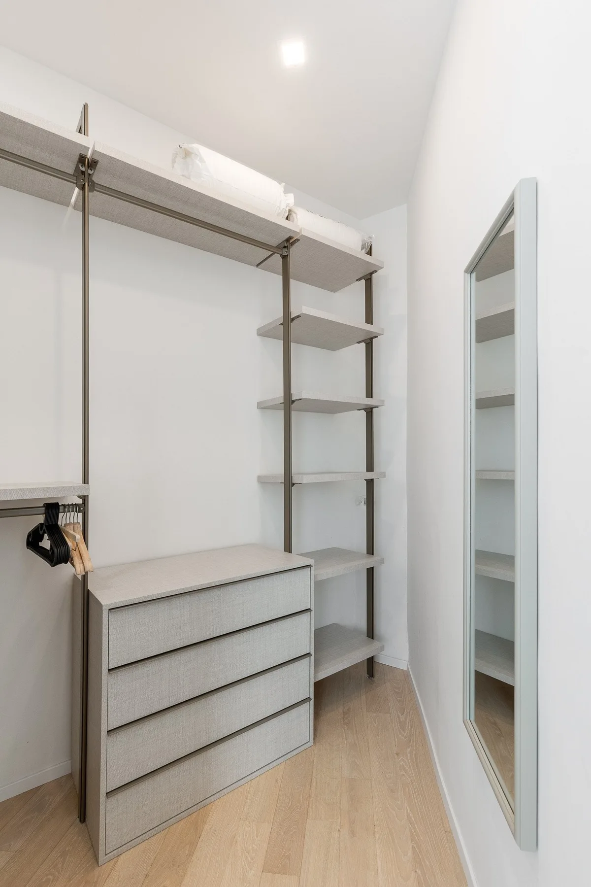 A bright walk-in closet with open shelving, hanging space, and a drawer unit.