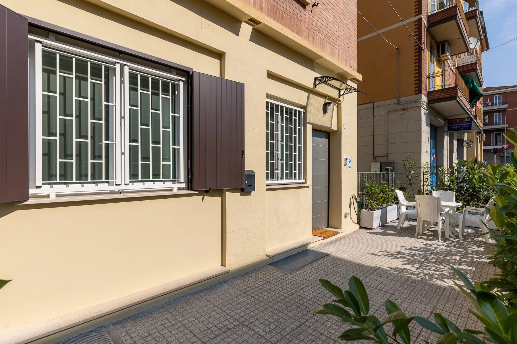 A paved outdoor patio beside a building, with seating and plants.