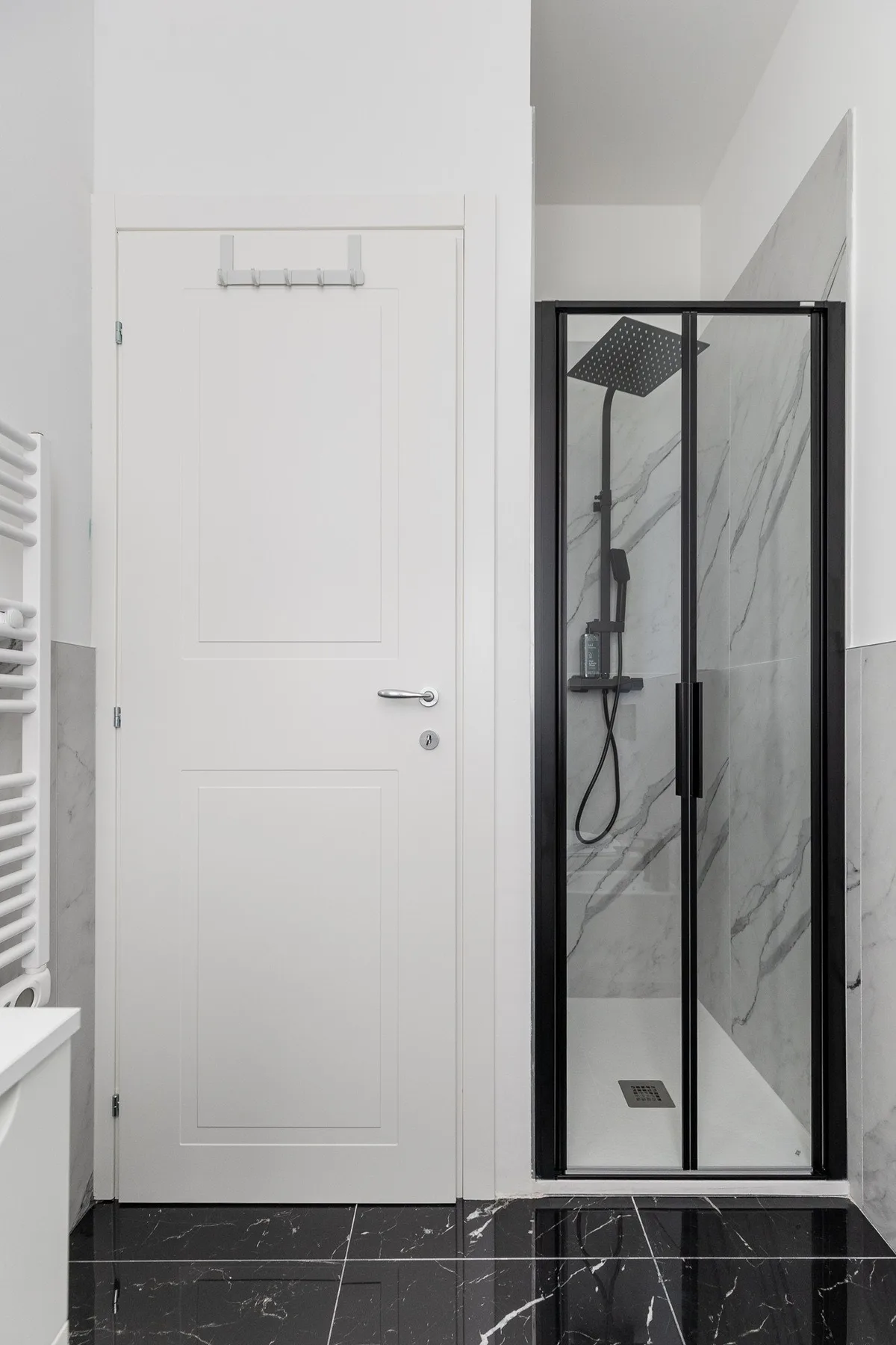 A bright bathroom with a glass shower beside a white paneled door.