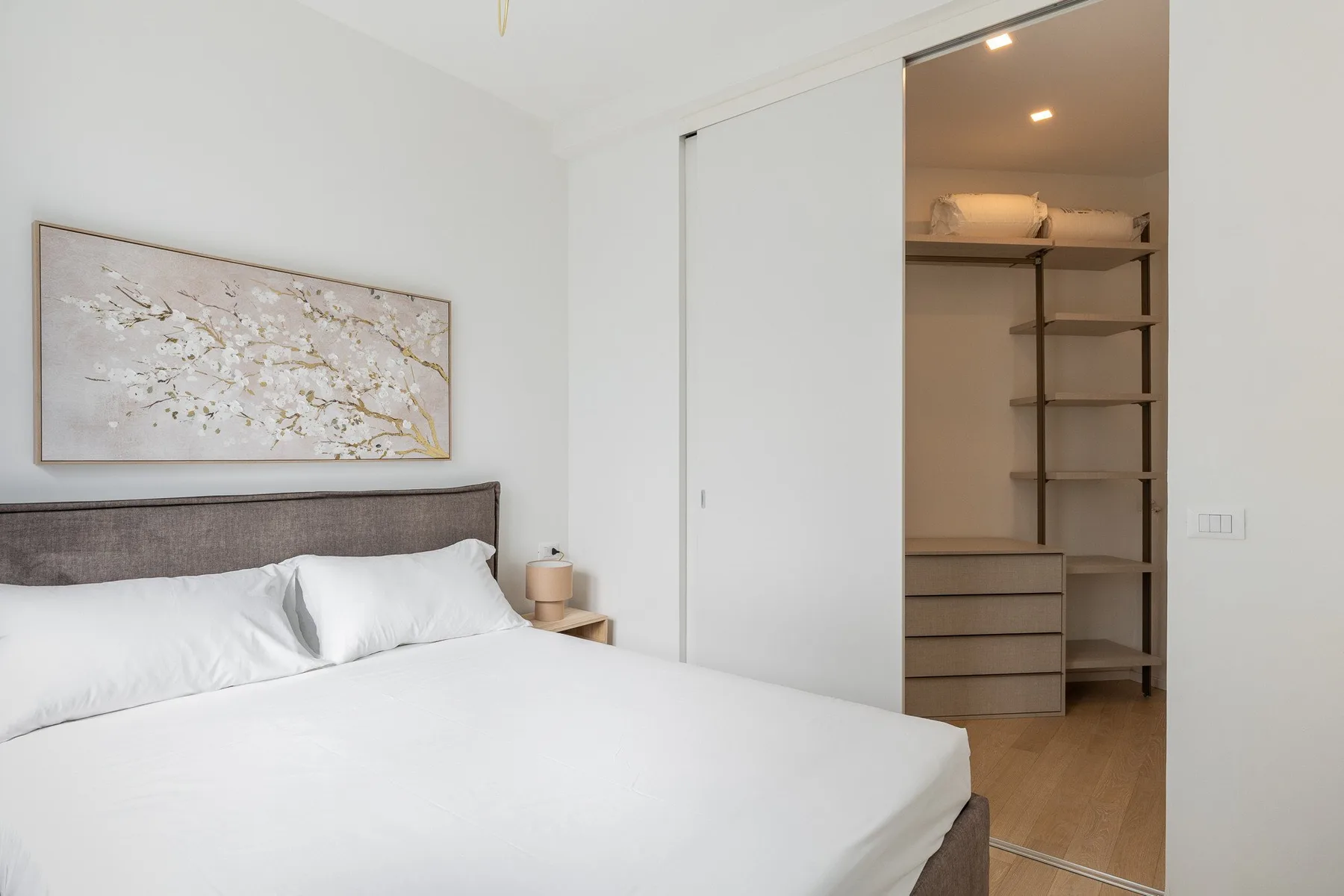A bright bedroom with a bed and an open closet.
