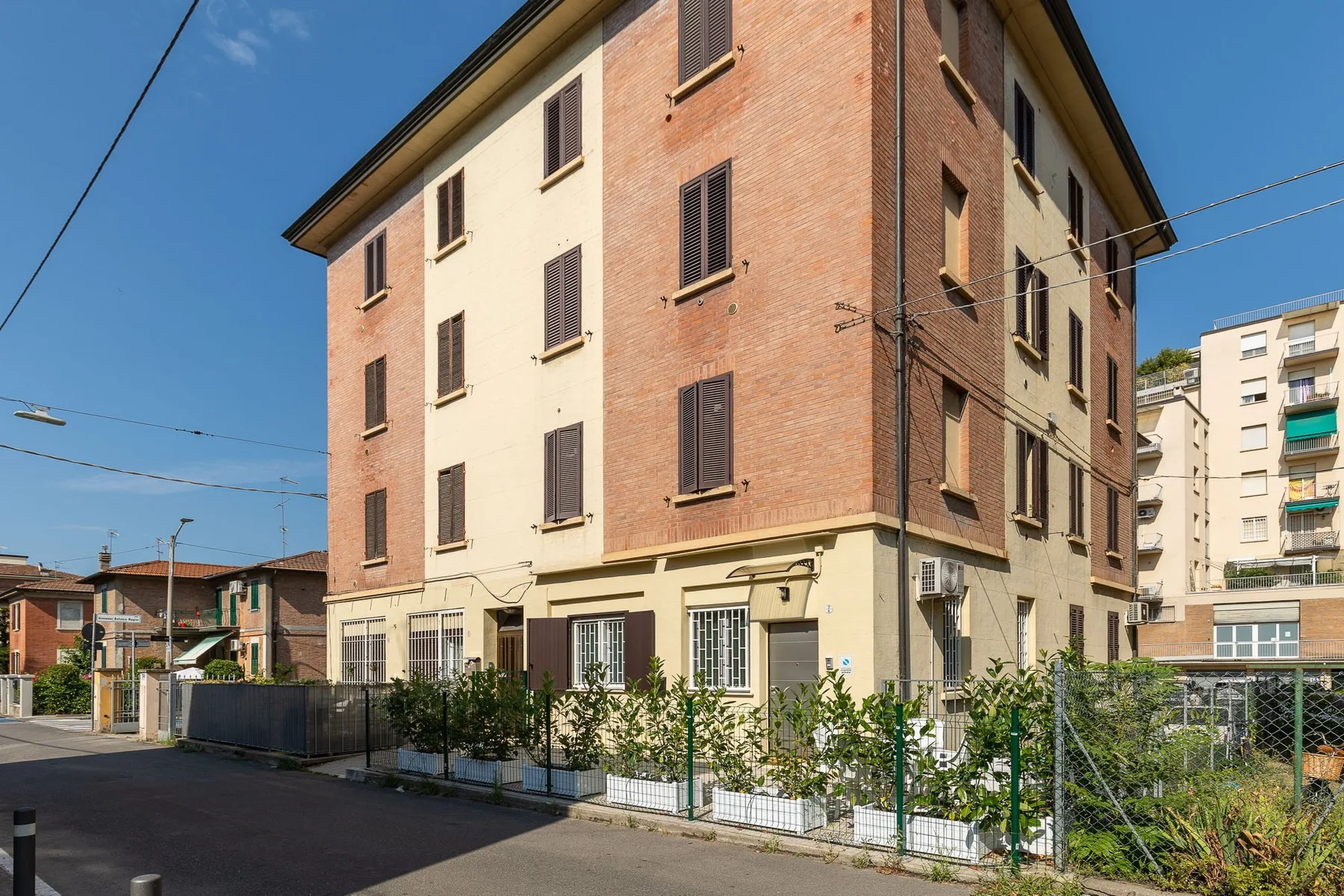A multi-story brick and stucco apartment building stands beside a residential street.