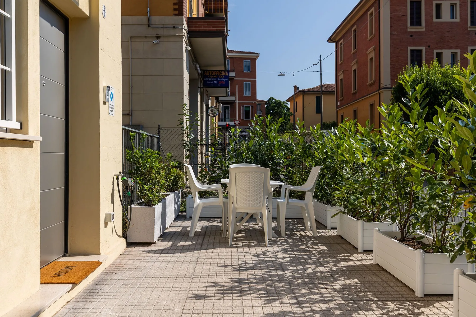 A paved outdoor seating area with white chairs and planters.