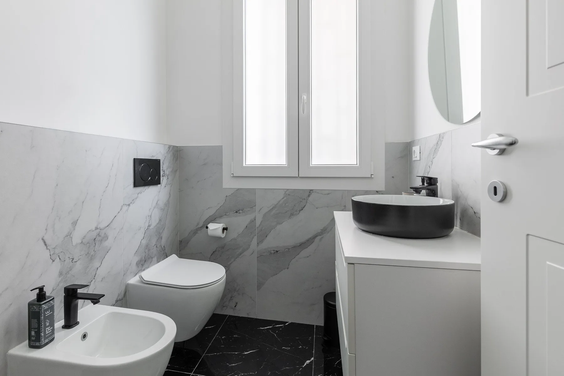 A bathroom with a sink, toilet, and window.