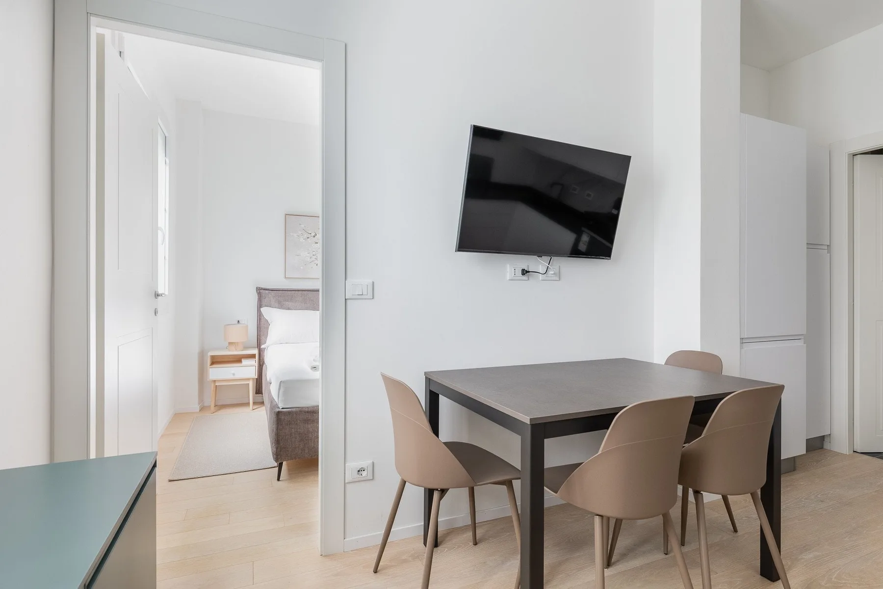 A dining area with a table and seating beneath a wall-mounted television.