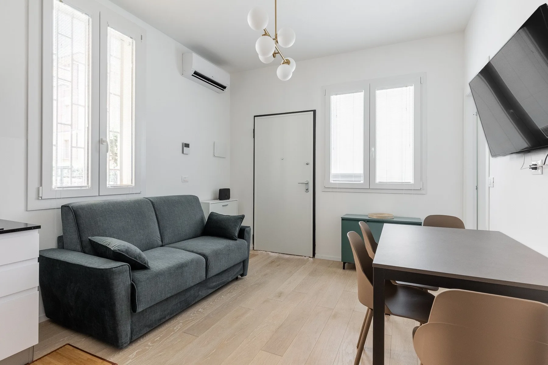 Una luminosa sala de estar y comedor con asientos, una mesa y ventanas altas.