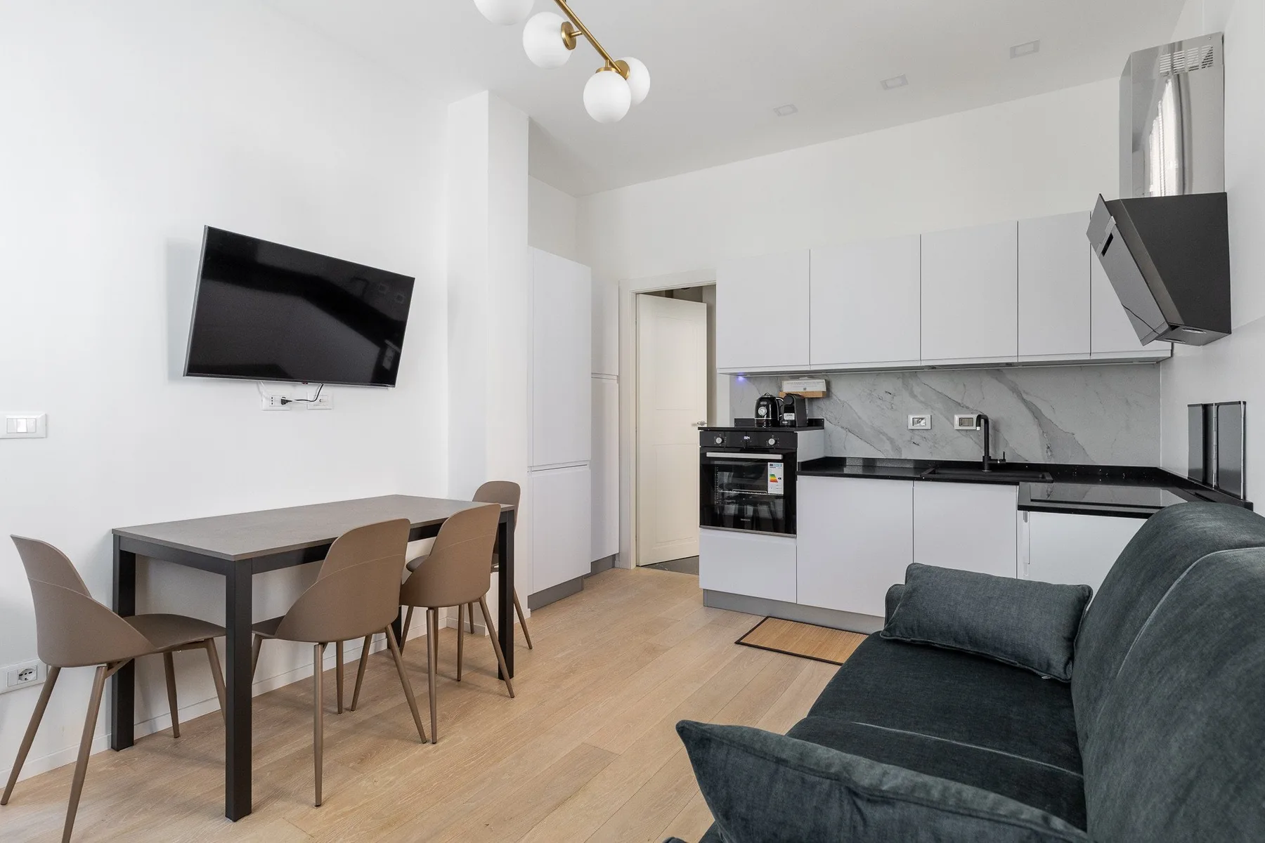 Una luminosa cocina y comedor con armarios blancos y una mesa junto a la zona de estar.