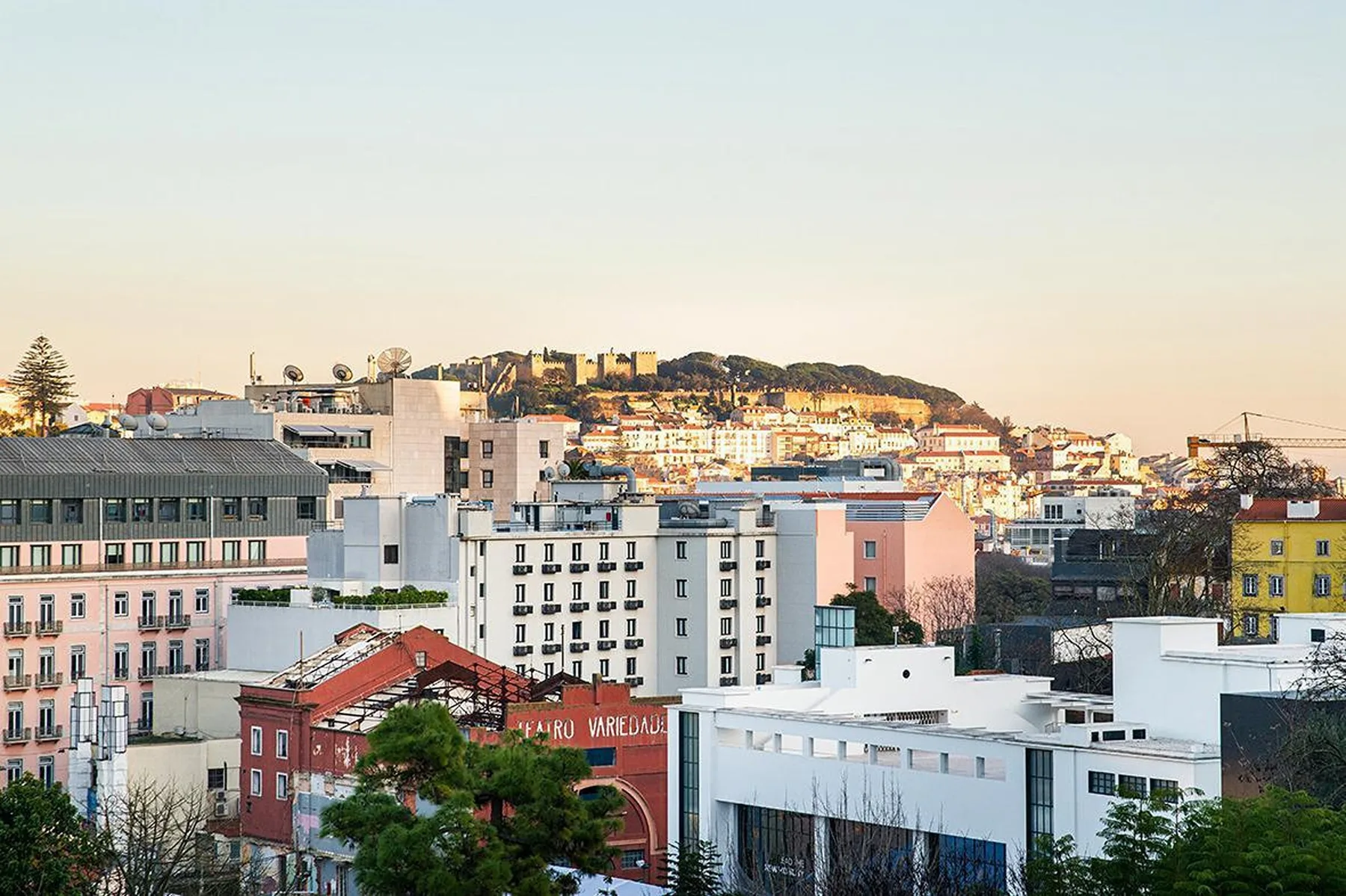 Paisaje urbano de Lisboa con edificios agrupados y una colina a lo lejos.