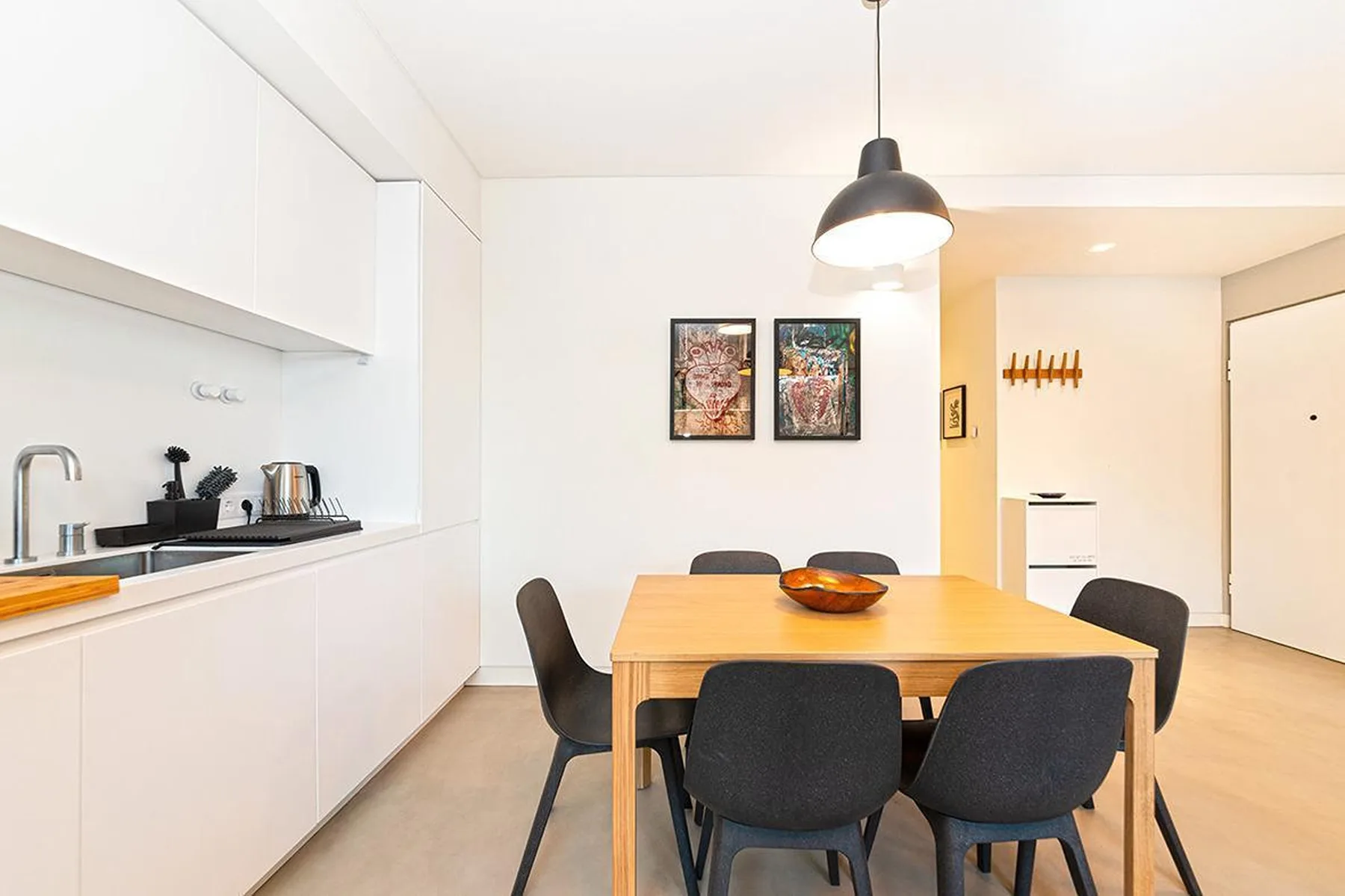 Una cocina y comedor luminosos con una mesa de madera y asientos oscuros.