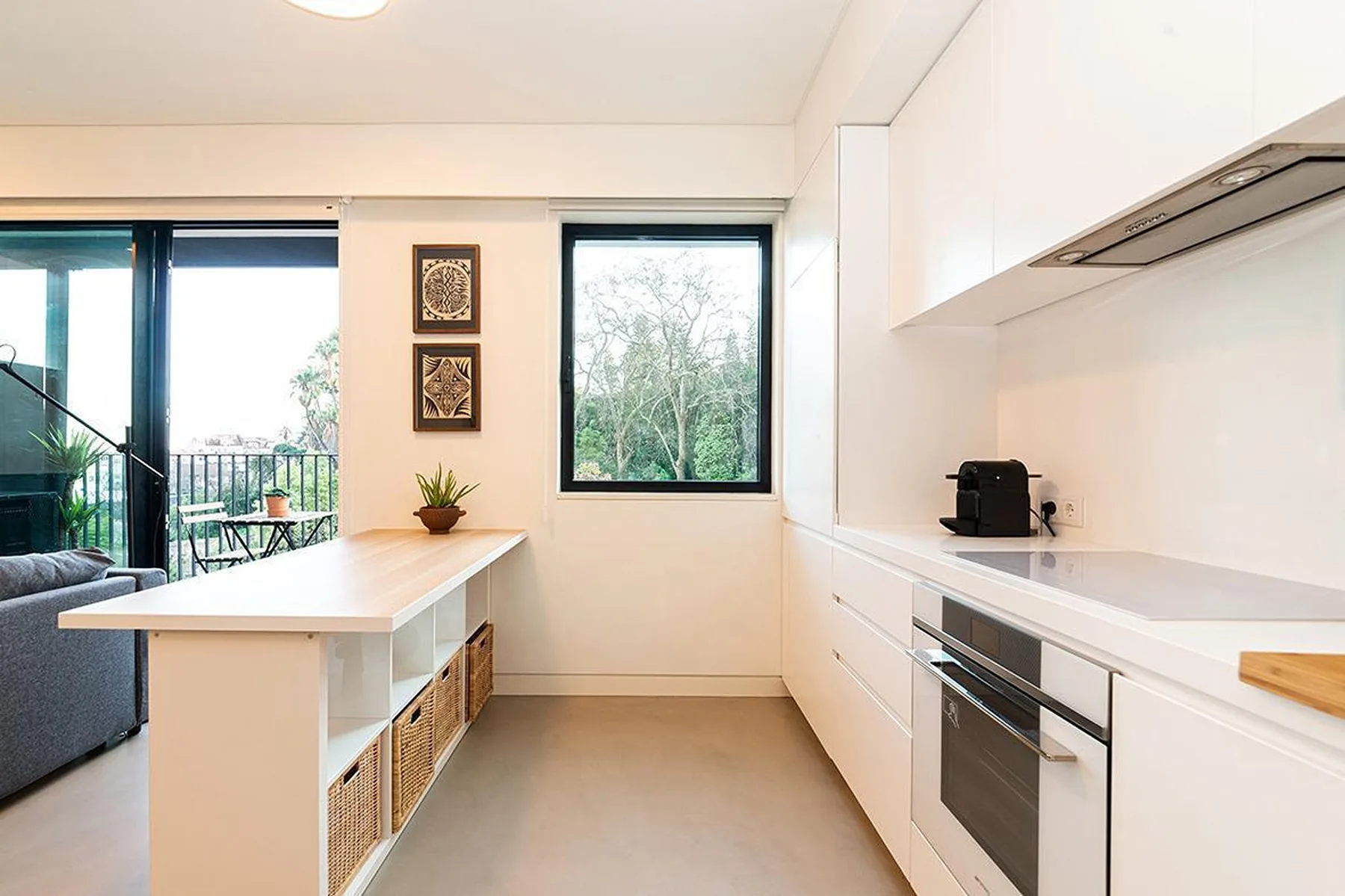Una cocina moderna y luminosa con gabinetes blancos, una isla y grandes ventanas.