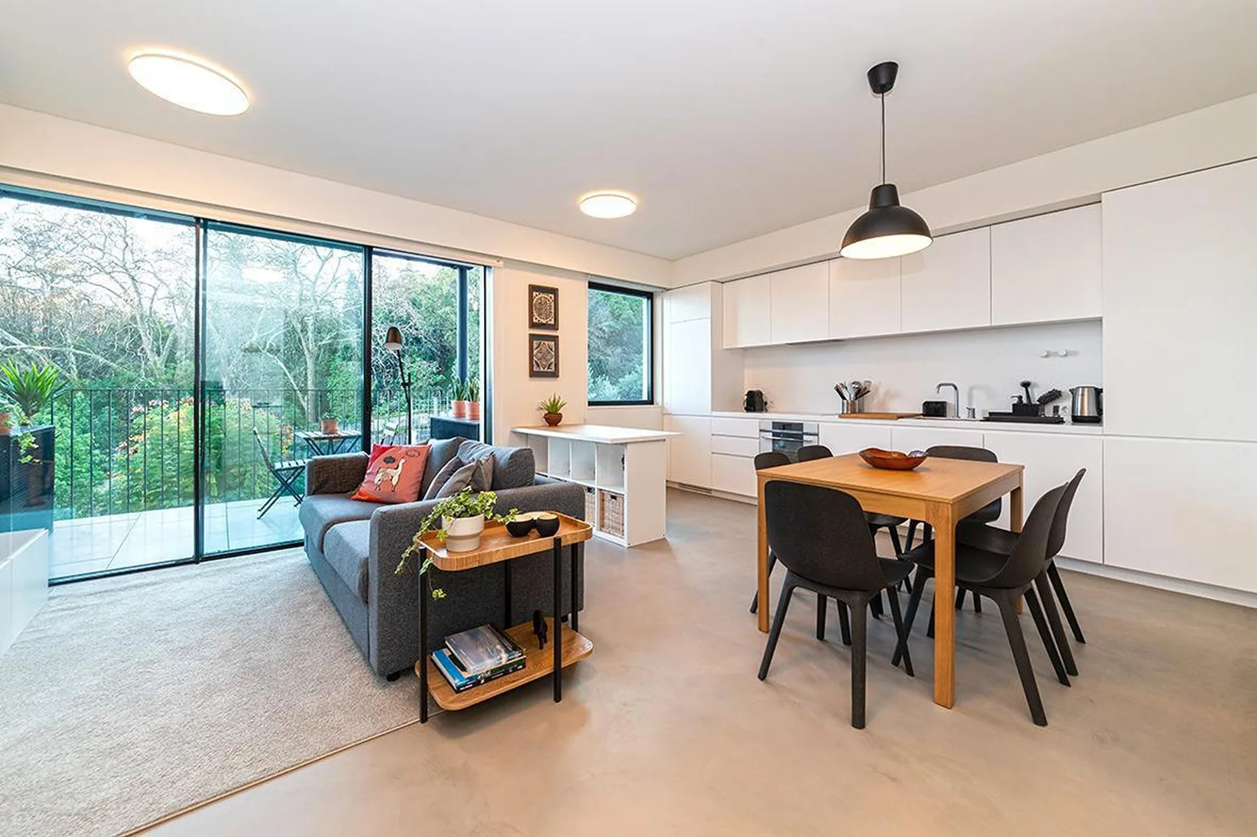 Una sala de estar y comedor diáfana con cocina y grandes puertas de cristal.
