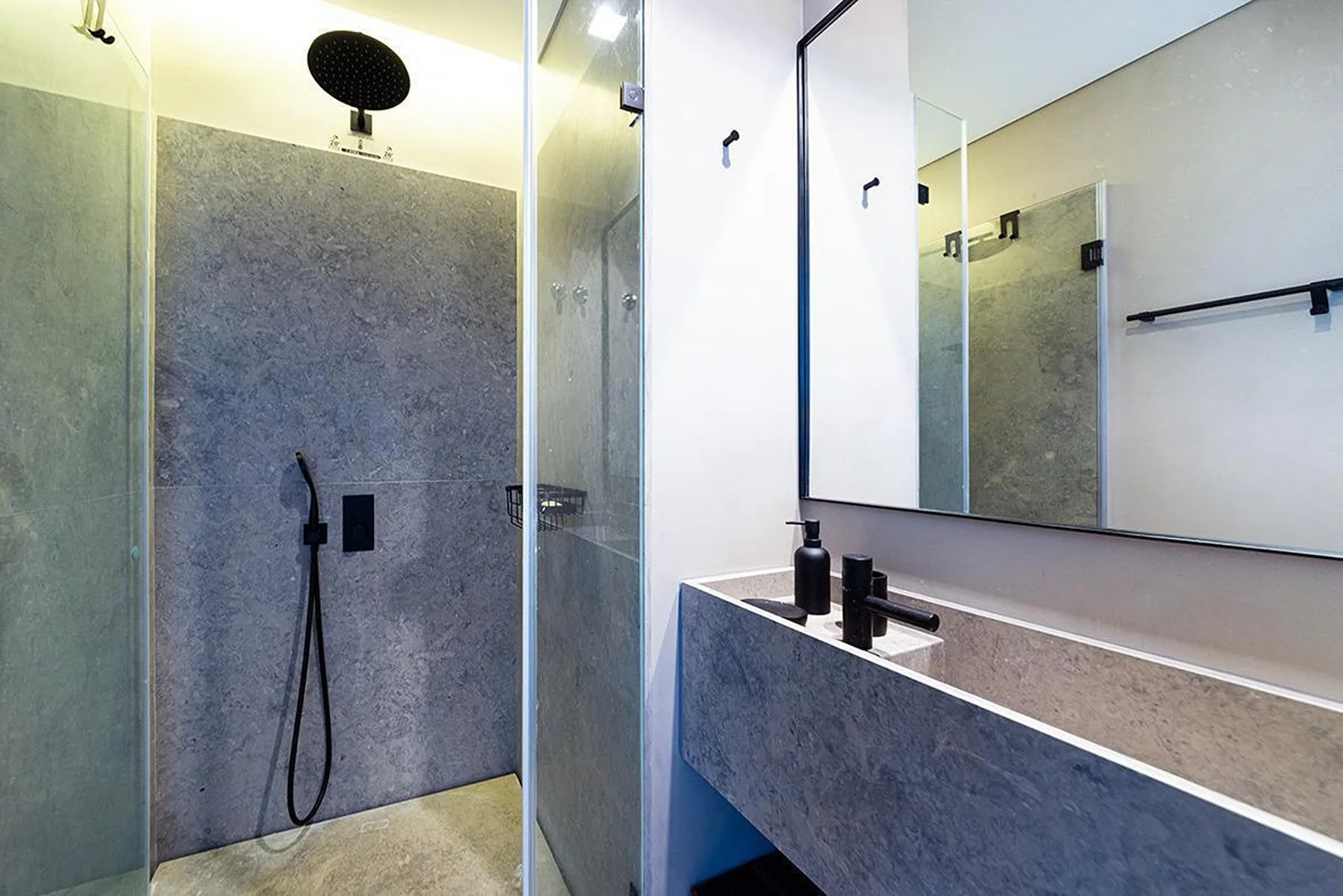Un baño moderno con ducha y un amplio lavabo bajo un espejo.