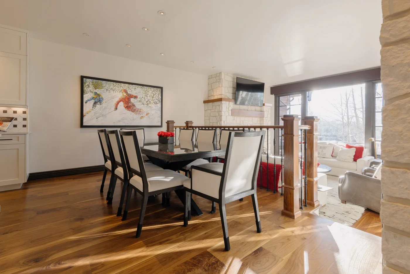 Un comedor con una mesa larga y sillas junto a grandes ventanas.