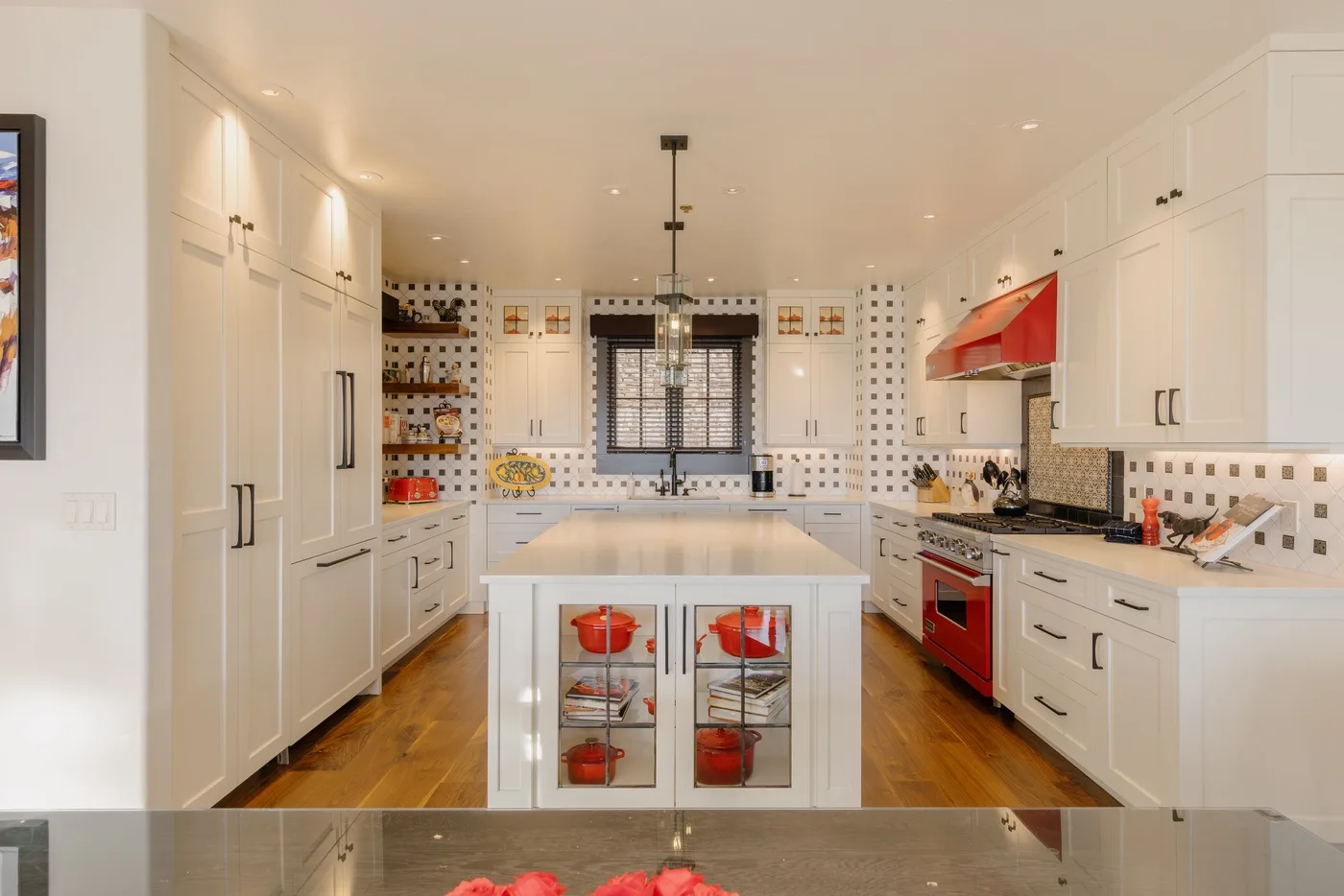 Una cocina luminosa con gabinetes blancos, azulejos decorados y una isla central.