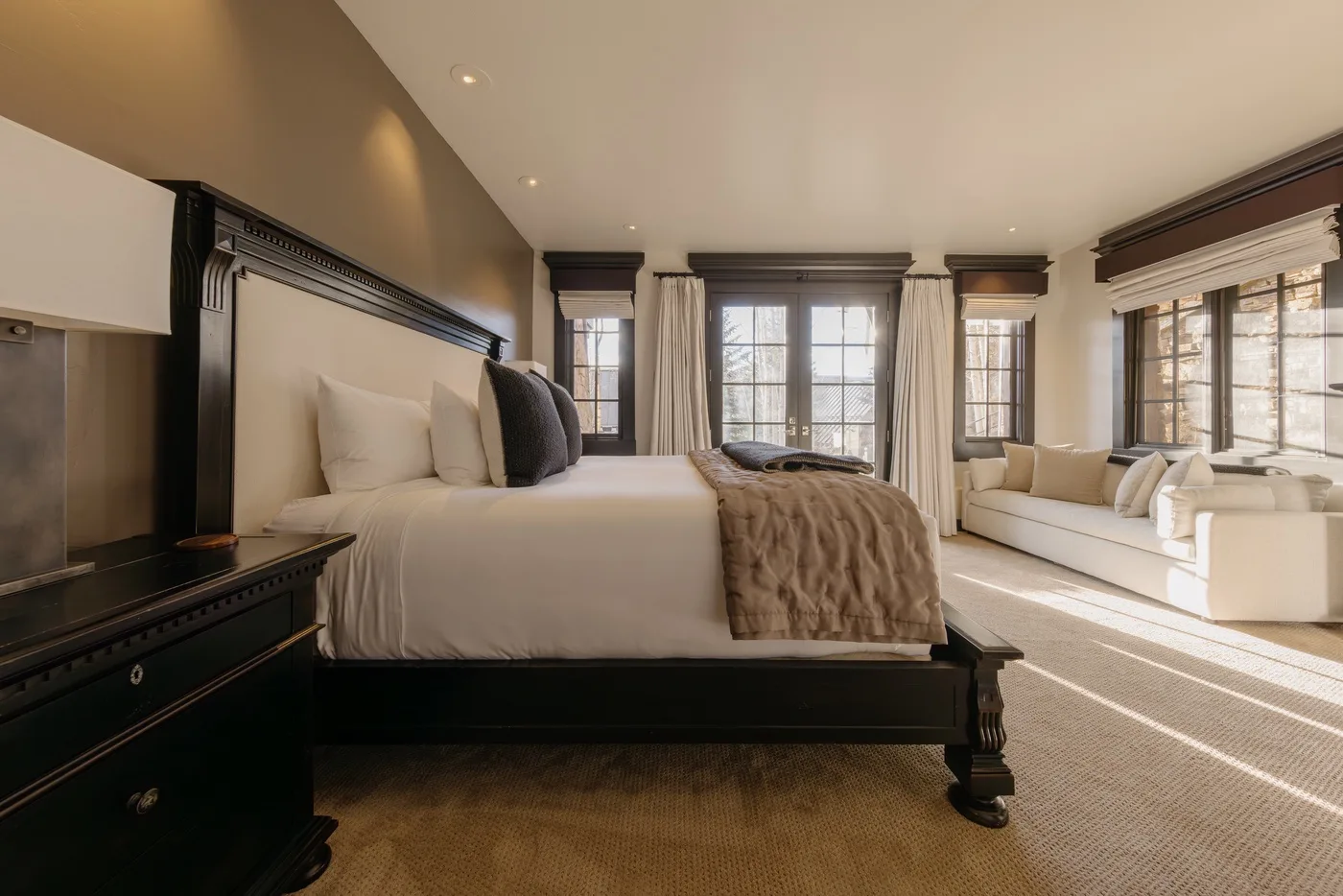 Un dormitorio amplio con una cama grande y una zona de estar junto a ventanas altas.