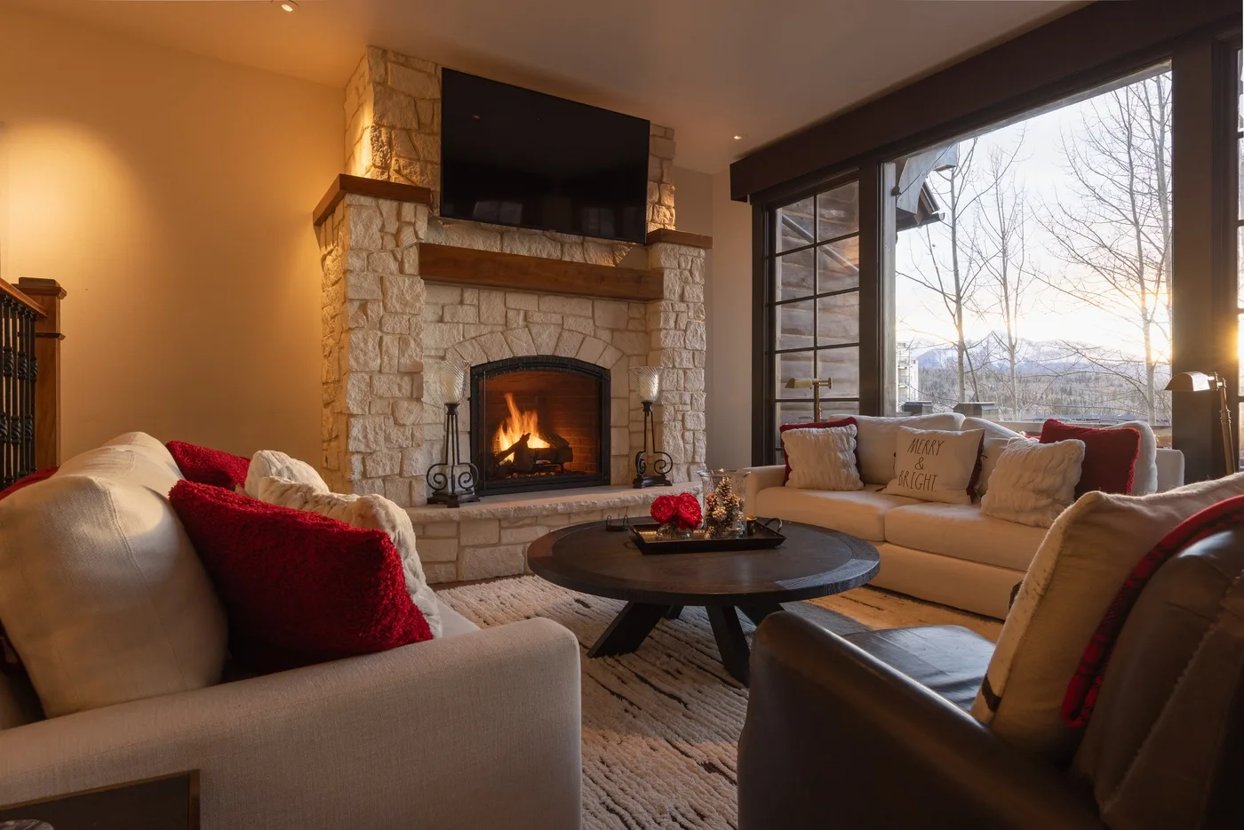 Una sala de estar con asientos alrededor de una mesa de centro y una chimenea de piedra.