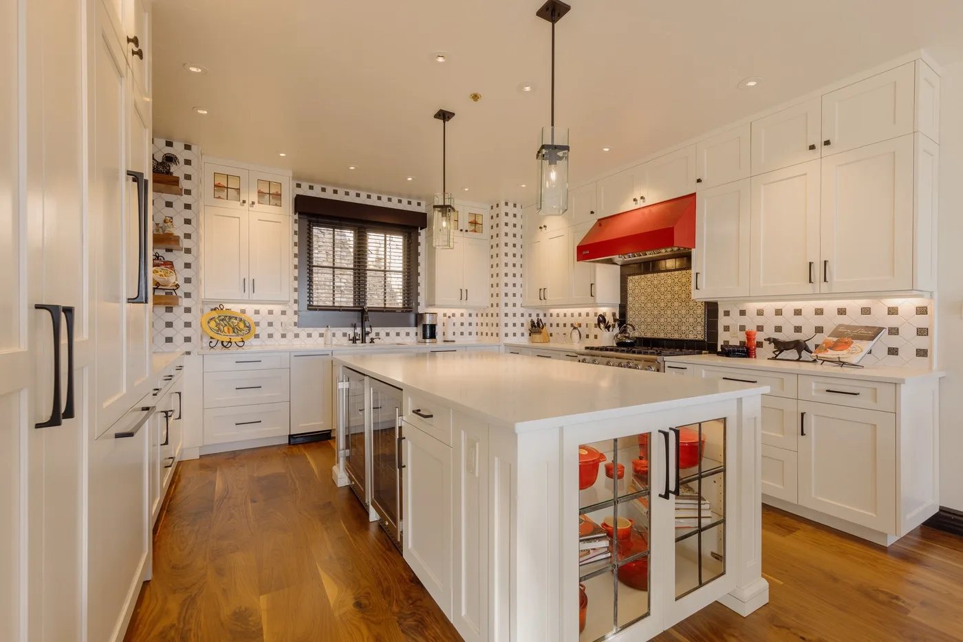 A bright kitchen with white cabinetry, a central island, and a red range hood.