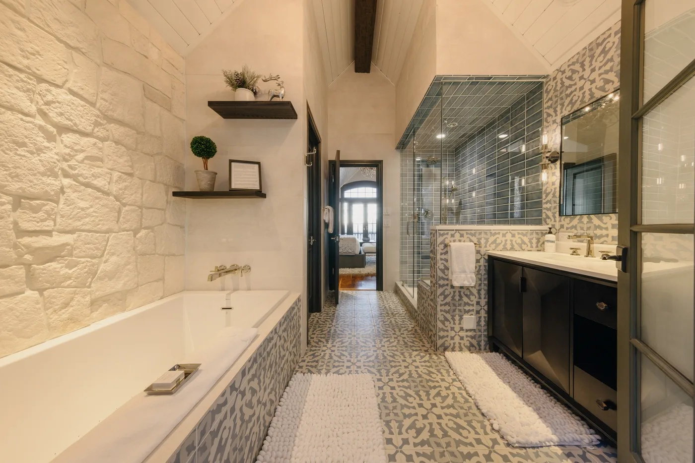 Un baño con bañera, azulejos estampados y un lavabo.