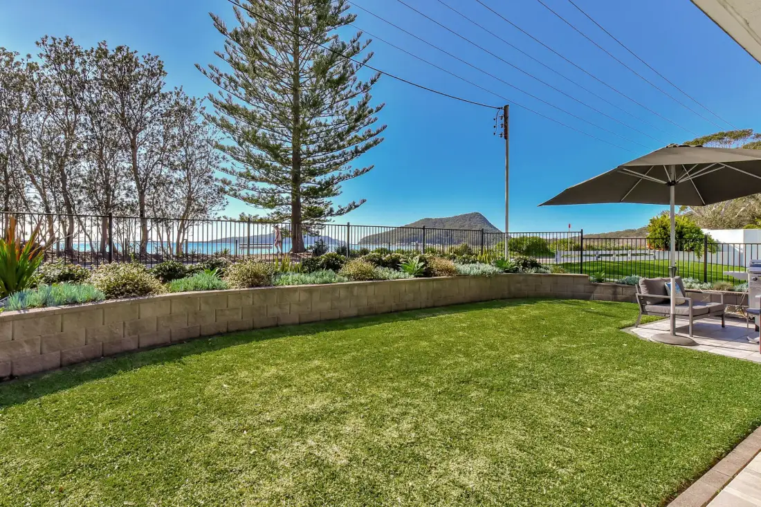 A landscaped lawn and outdoor seating area overlook the water.