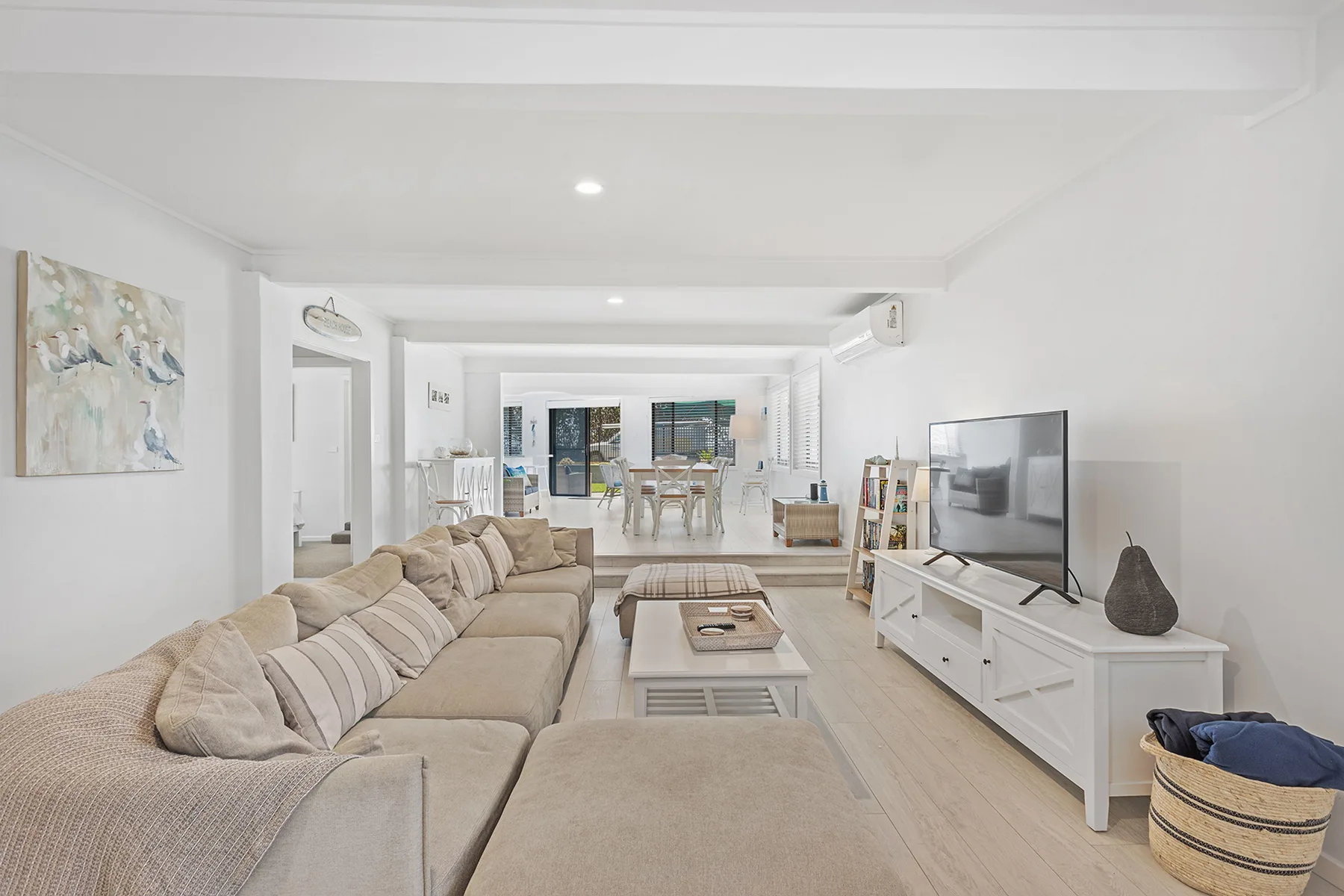 A bright living room with seating, a coffee table, and a television.