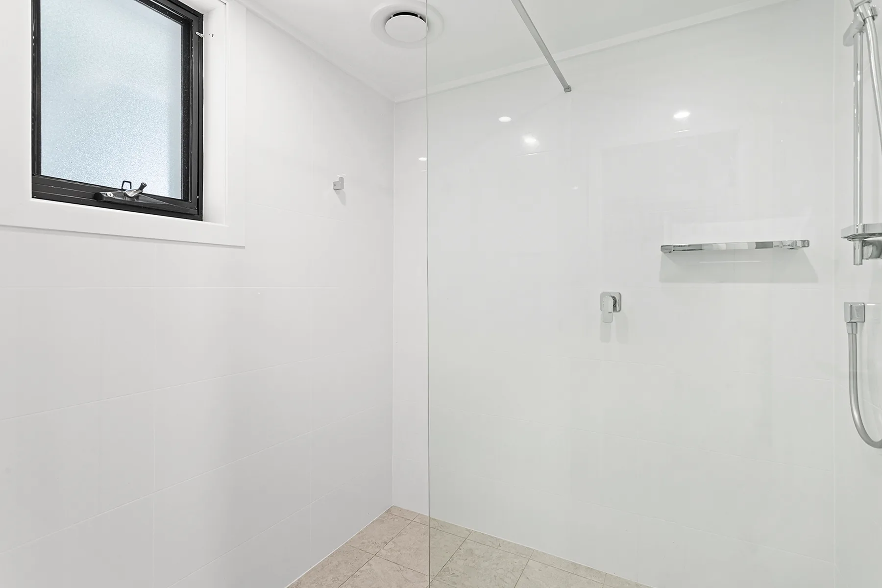 A bright bathroom with a shower and a small window.